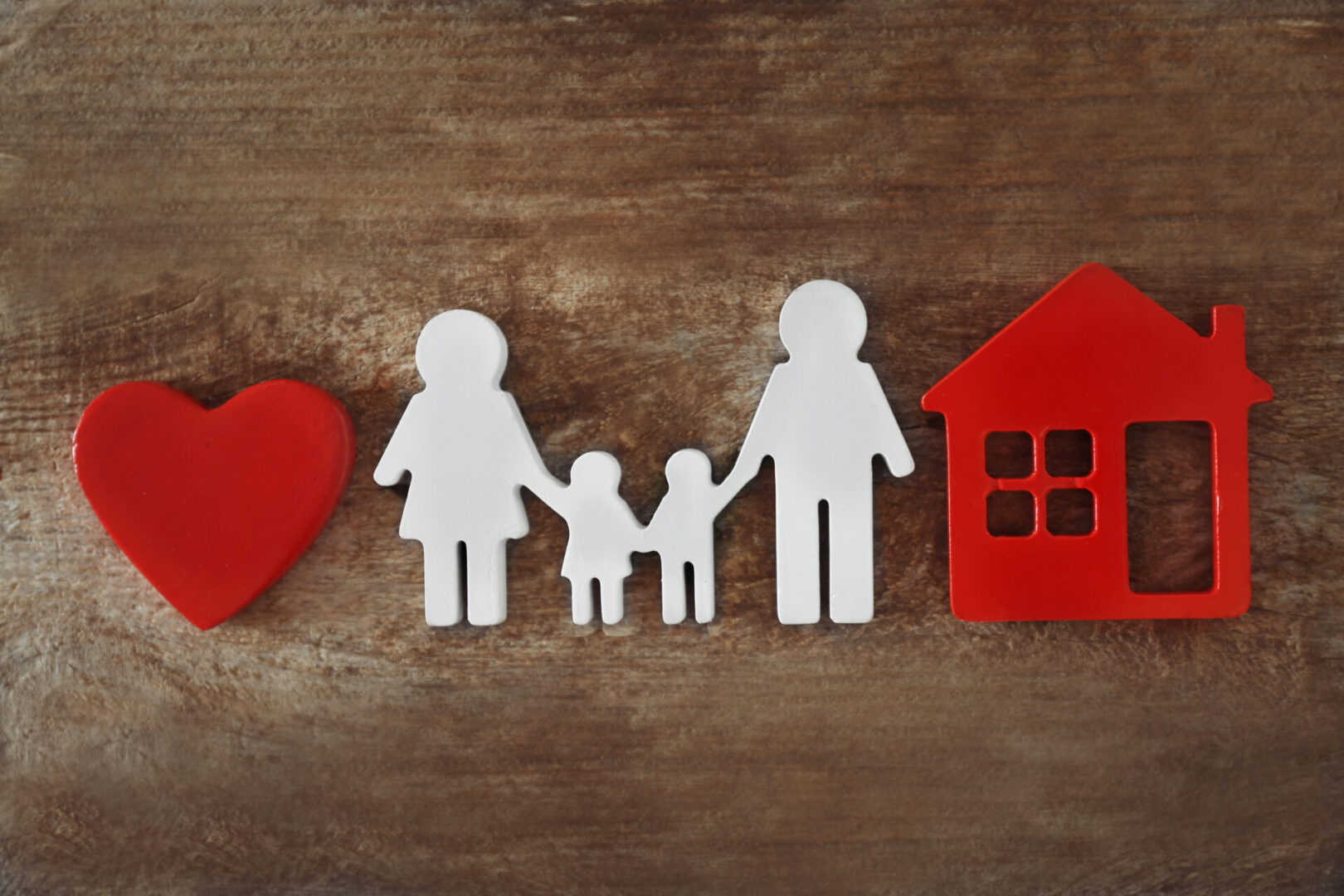 Family,Figure,With,A,House,On,Wooden,Background